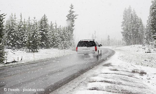 Schnee Ein Auto fährt bei Schneefall auf einer Straße